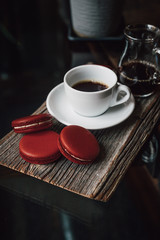 Macaroons with cup of coffee on wood plate, blur in background
