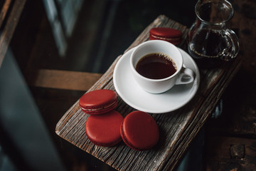 Macaroons with cup of coffee on wood plate, blur in background