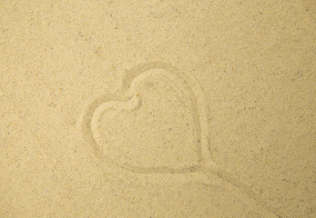Fototapeta na wymiar Heart drawn in the sand. Beach background. Top view