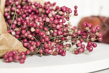 Rosa Pfefferbeerenstrauch auf einem weissen Holzbrett