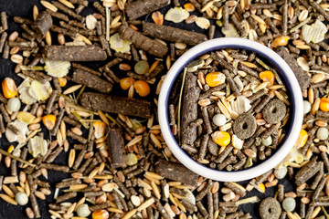 dry food for rodents in bowl dark background top view