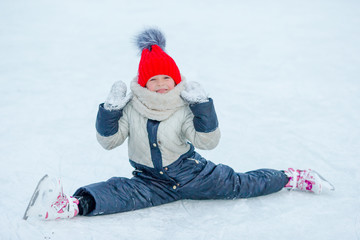Fototapeta na wymiar Little adorable girl sitting on ice with skates after fall