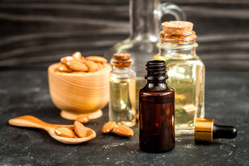 cosmetic almond oil in glass bottle on dark wooden background