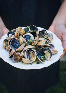 A woman holds a plate of Grilled Clams