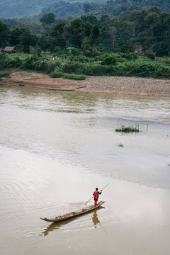 A man crossing the Mekong River on his wooden boat