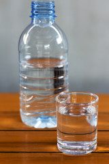 Drinking water in the glass and in the bottle on a wooden table.