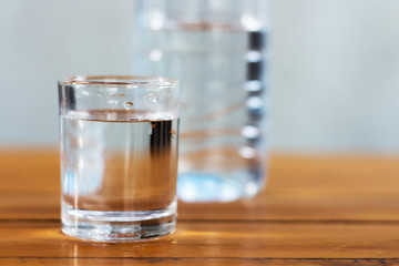 Drinking water in the glass and in the bottle on a wooden table.
