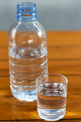 Drinking water in the glass and in the bottle on a wooden table.