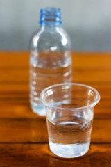 Drinking water in the glass and in the bottle on a wooden table.