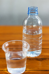 Drinking water in the glass and in the bottle on a wooden table.
