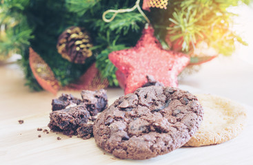 Chocolate cookies on a wooden background with Christmas tree branches and warm light decorations