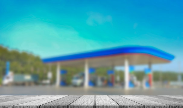 White wooden tabletop with blurred of gas station on blue sky background use for products display