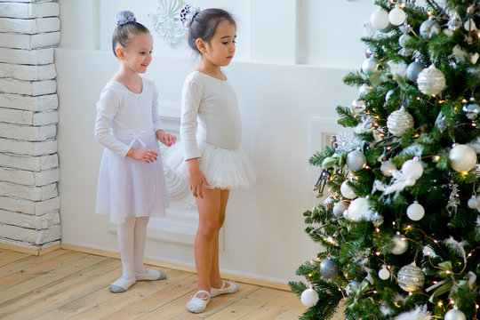 Two young ballet dancers learning the lesson near Christmas tree