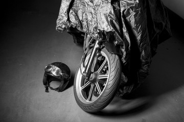 Black and white shoot of a covered retro motorbike at garage