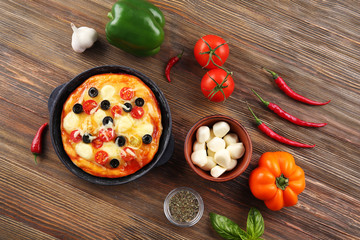 Delicious pizza with ingredients and spices on table