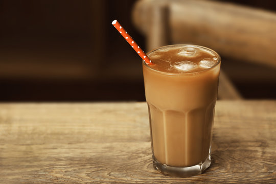 Glass of cold coffee on wooden table