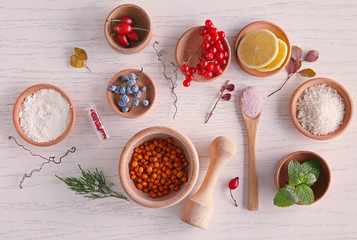 Natural ingredients for homemade cosmetics in wooden bowls on white table