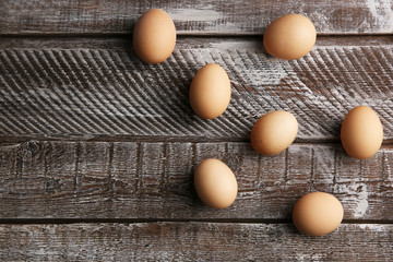 Raw eggs on wooden background, top view