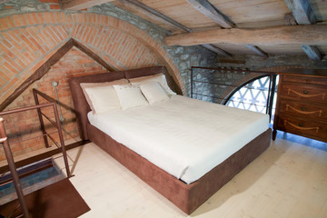 Double bed on a mezzanine in a rustic loft on the hills - obrazy, fototapety, plakaty