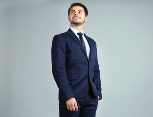 Fototapeta premium Handsome young businessman on gray background