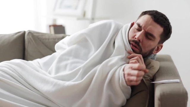 ill man with thermometer having flu at home