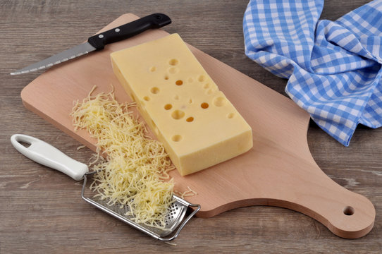 Emmental sur une planche à découper avec une râpe à fromage et de l'emmental râpé 