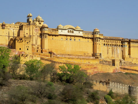 View of part of the fortress walls and towers of the ancient fort Amber on the hill lit midday sun. Jaipur, India.