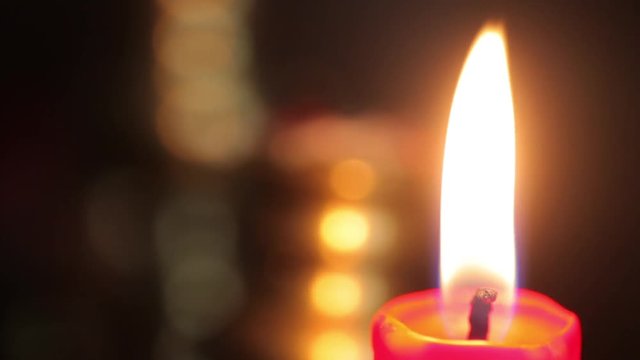 Color footage of a candle burning in a candlestick.