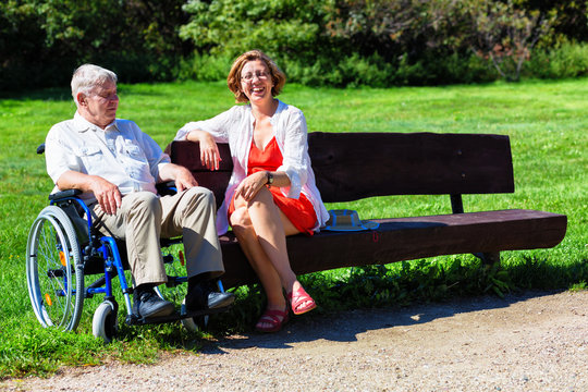 old man on wheelchair and young woman on a bench