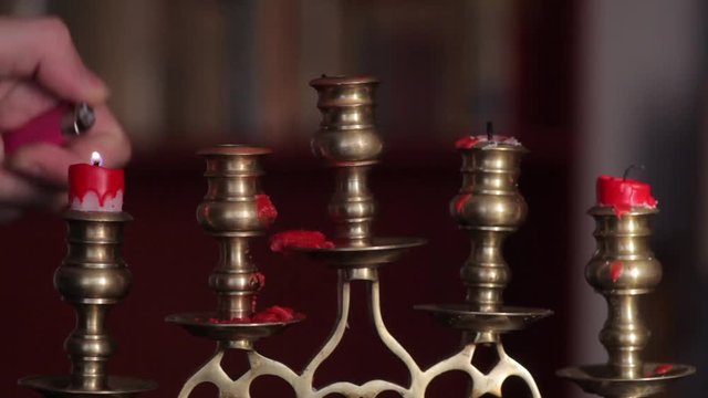 Color footage of two candles in a candlestick, and a hand lighting it with a lighter. 