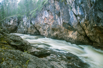 A beautiful scenery with a river rapids at the red cliffs in Finland