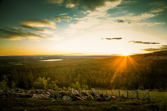 A beautiful landscape with a midnight sun above arctic circle. Dreamy scenery with light flares