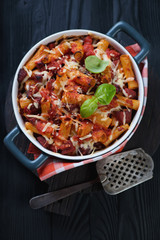 Baking dish with italian ziti, black wooden surface, top view
