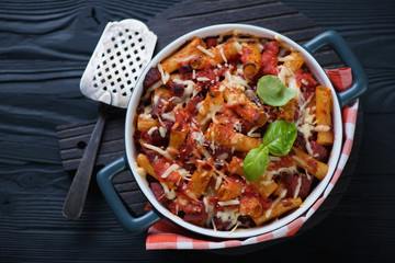 Casserole with ziti over black wooden background, above view