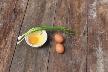 Raw egg in a bowl selective focus and onion on wooden
