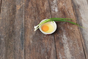 Raw egg in a bowl selective focus and onion on wooden table