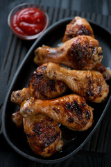 Barbecued chicken legs served in a cast-iron frying pan, closeup
