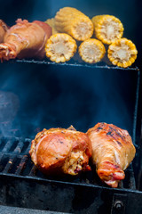 Close-up of appetizing turkey legs on the grill with corn cob. Concept summer picnic outdoors