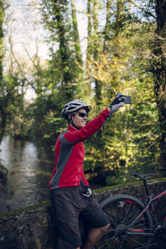 Mountain biker taking picture in forest with his smart phone