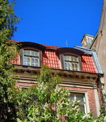 Fototapeta na wymiar Red roof, dormers and flowering lilac