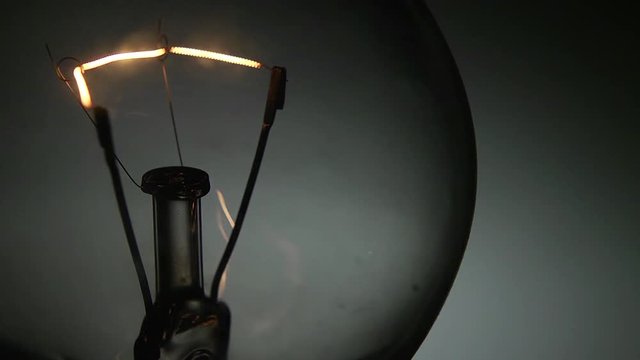 Dettaglio laterale del filamento di una vecchia lampada al tungsteno che si accende e si spegne.