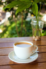 cup of fresh coffee with coffee beans on wooden table
