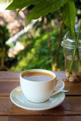 cup of fresh coffee with coffee beans on wooden table