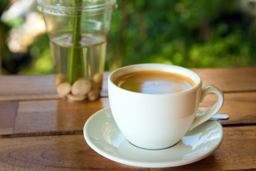cup of fresh coffee with coffee beans on wooden table