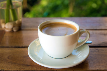 cup of fresh coffee with coffee beans on wooden table