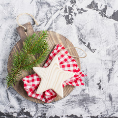 Simple Christmas background with a wooden board,  star and  fir branch on  light gray marble . Top view