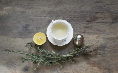 Cup of tea with mint and tea strainer on old wooden table