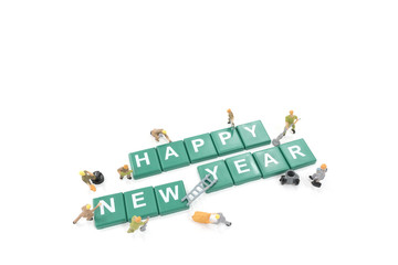 Miniature worker team building word happy new year on white back