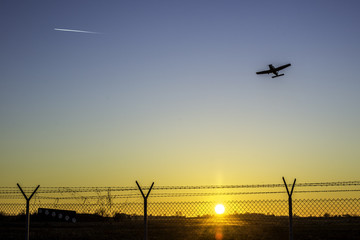 Flugzeug über einem Flugplatzgelände im winterlichen Sonnenuntergang