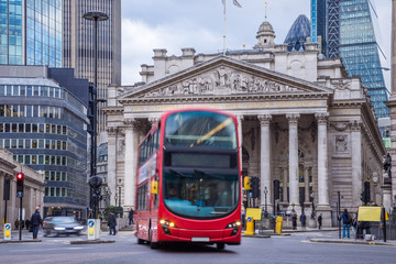 Fototapeta na wymiar London, England - Iconic red double decker bus on the move and the Royal Exchange building at background
